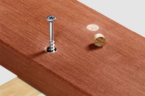 a hardwood board being fixed to a joist with a screw.