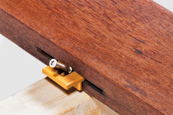 A hardwood board being fastened to a joist.