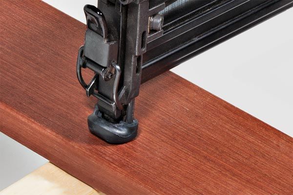 A hardwood board being nailed into a joist.