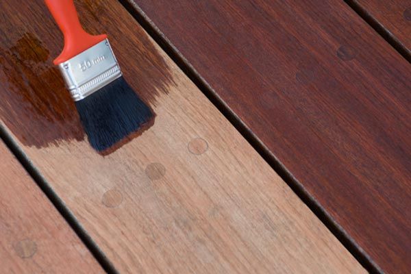 A paintbrush being used to freshen up the color of a hardwood joist.