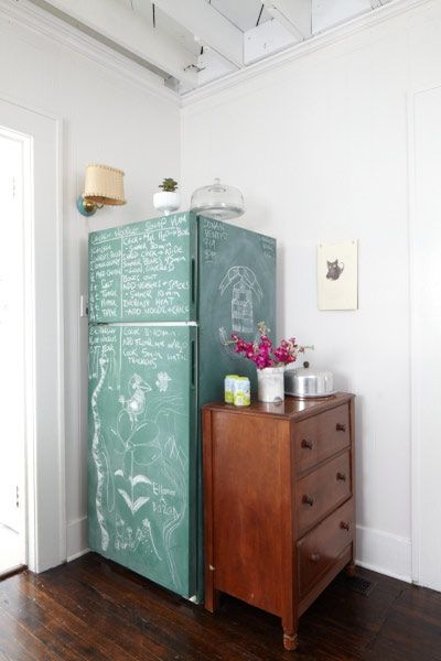 A refrigerator painted with chalkboard paint and covered an chalk writings and drawing.