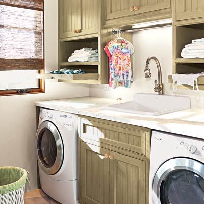 a laundry room with washer and dryer underneath the countertops on either side of a sink