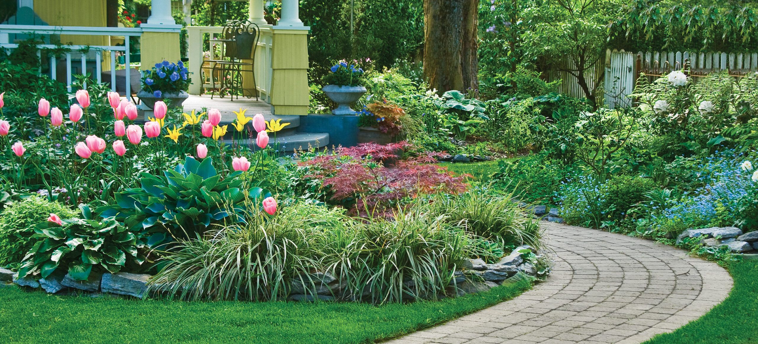 A DIY stone pathway passing through a garden with brightly colored flowers.