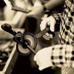 A person holds an antique hand-crank drill.