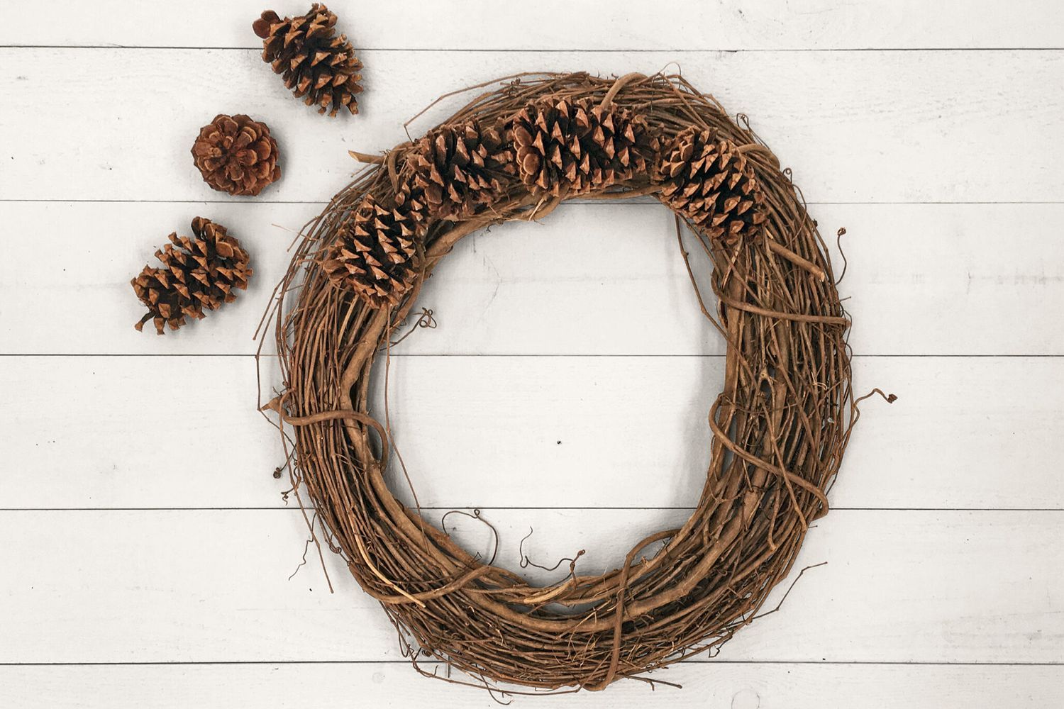 A wreath with a set of pinecones beside it.