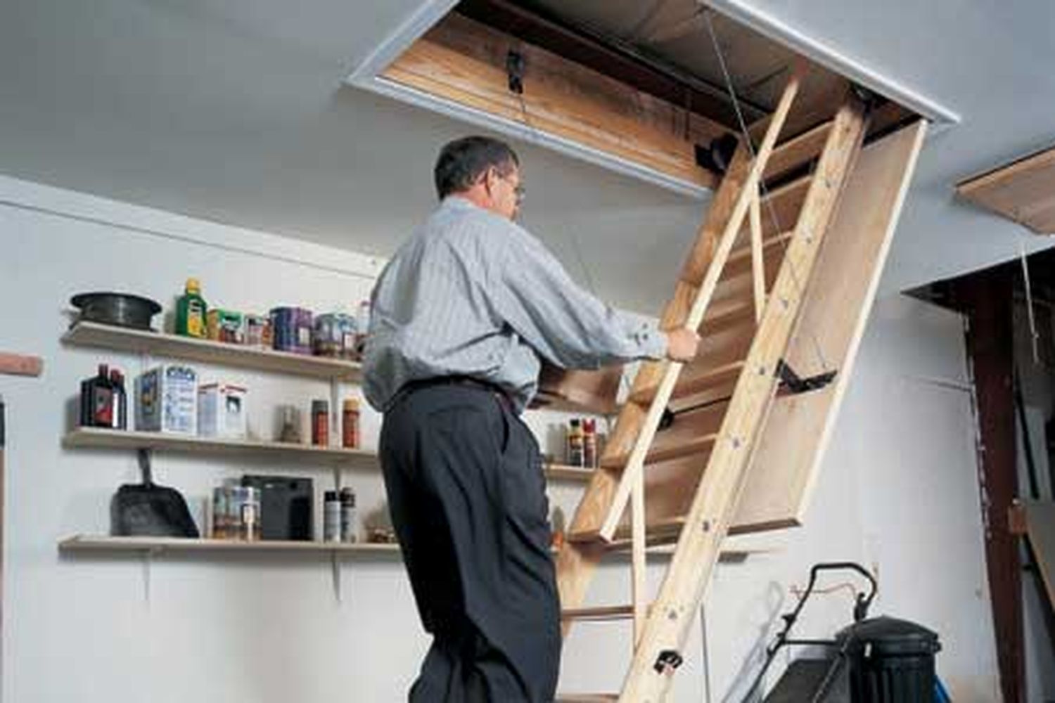 A man uses his newly installed pull-down attic stairs.