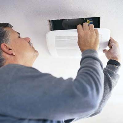 Tom Silva installs a bathroom fan in the ceiling.