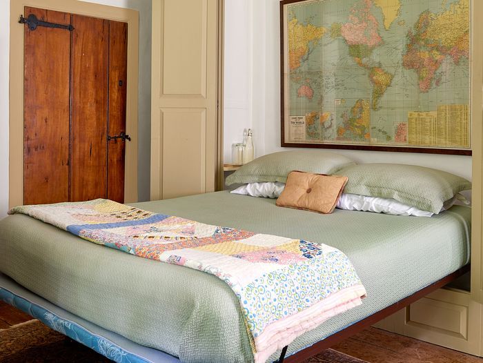 a murphy bed next to a door, it has a framed map above its head.