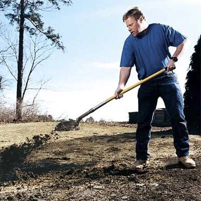 A man lifts and tosses away dirt with his shovel.