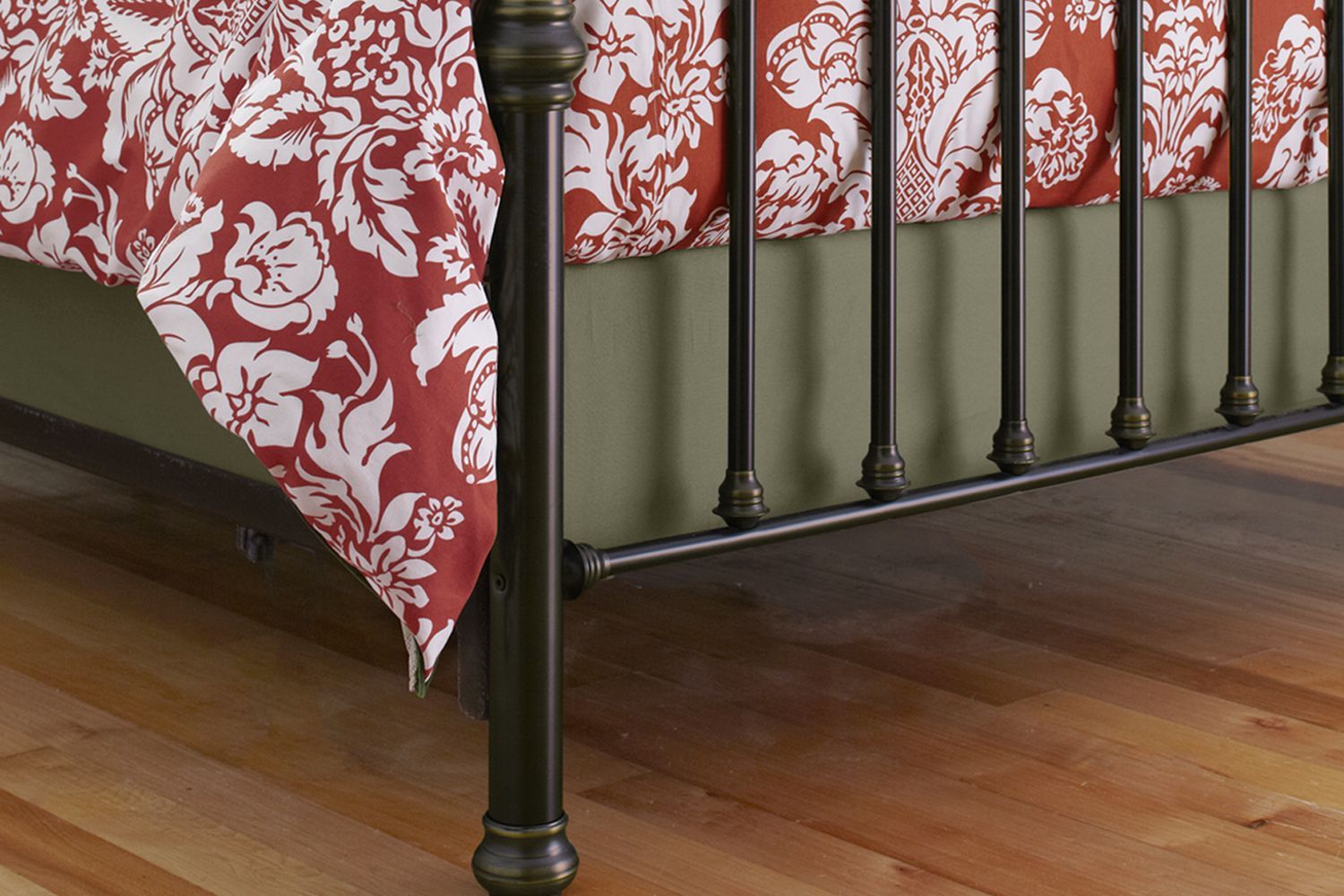 A box spring cover on a bed, it hangs just over the side.