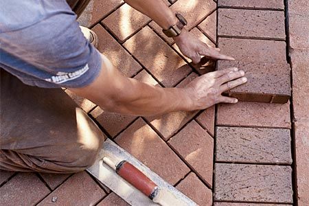 A man laying down bricks for a home patio.