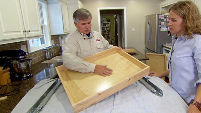 A man holding a slide drawer to be installed in a cabinet.