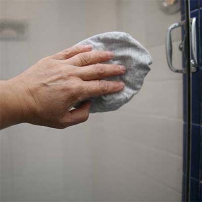 A clear door being wiped with a car wax soaked rag.