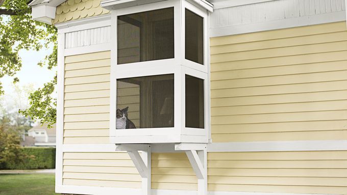 An outdoor catio attached to the side of a yellow house.