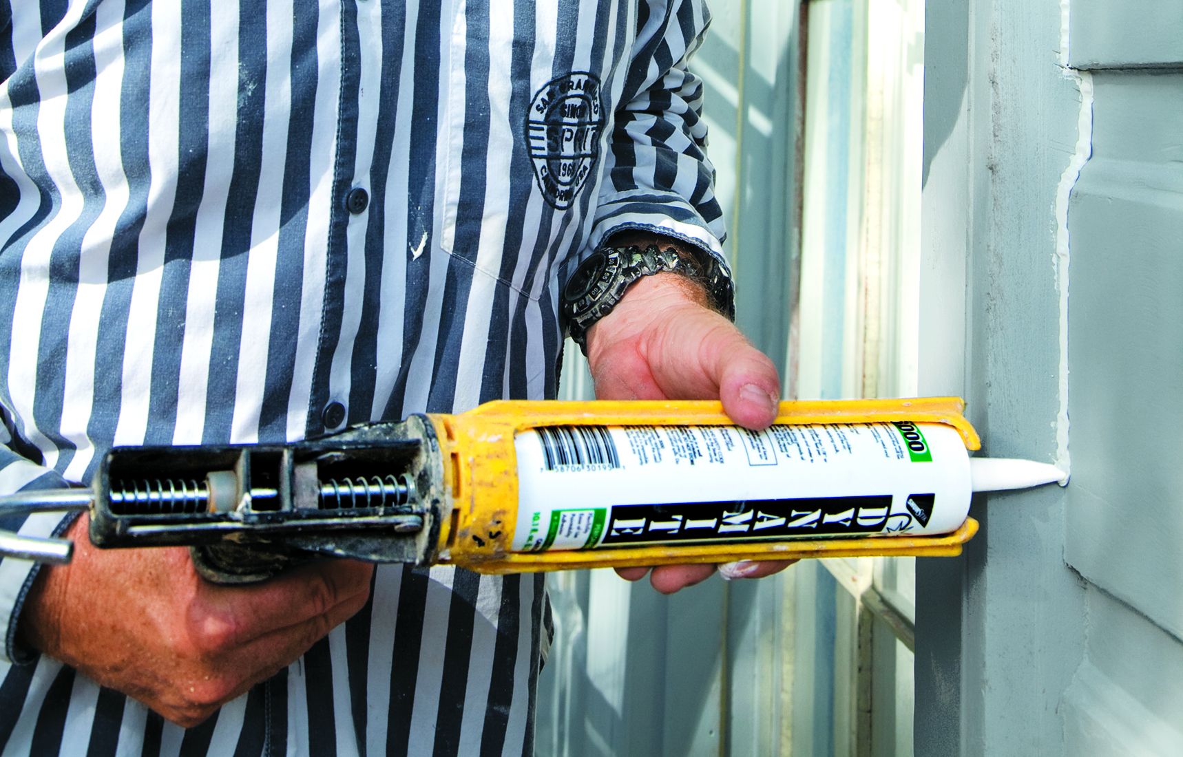 using a caulking gun to caulk around the edges