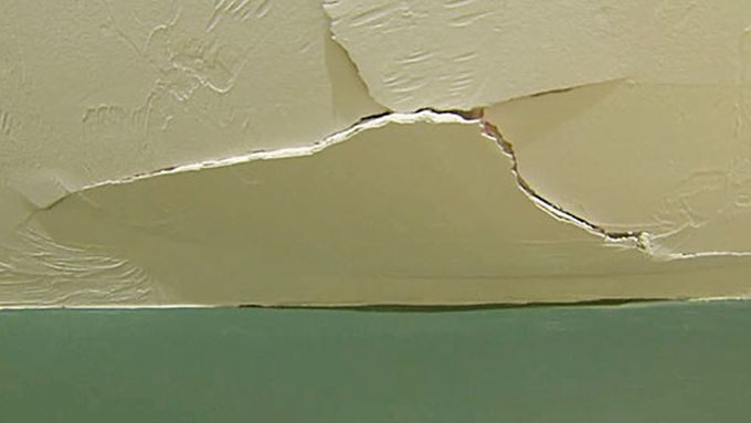 Cracked drywall on the ceiling of a room.