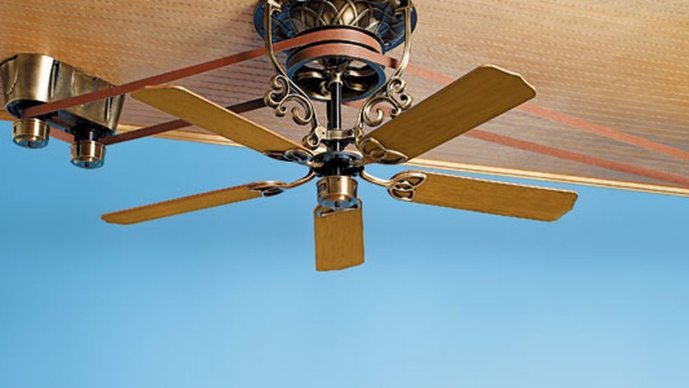 A ceiling fan on a brown ceiling.