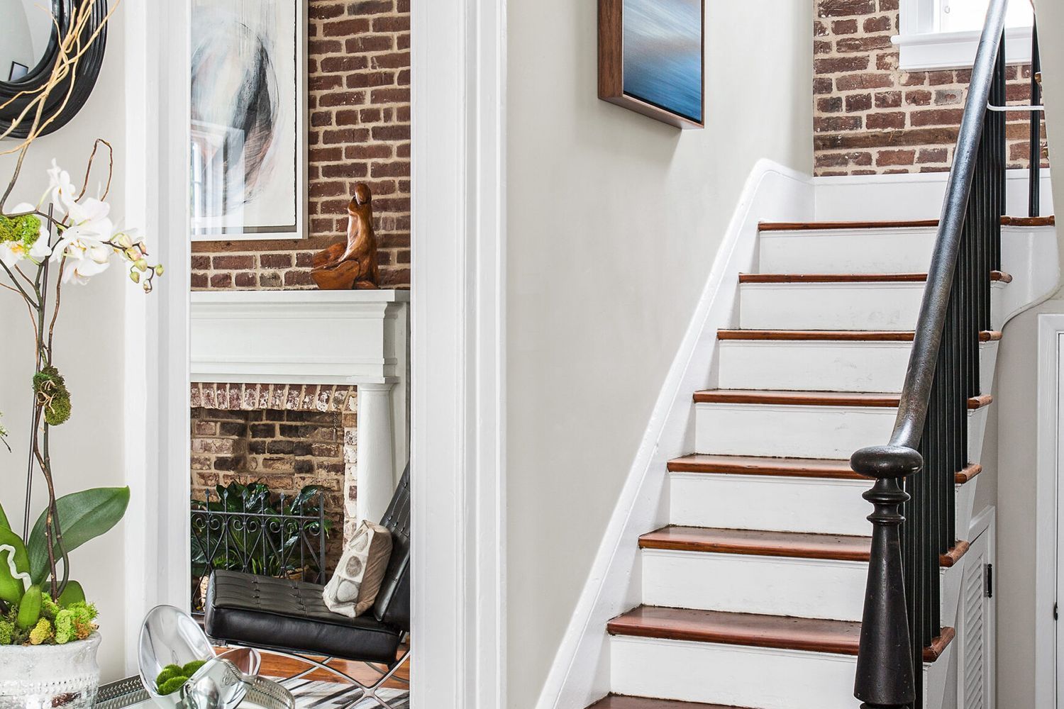 A entryway with a staircase featuring no carpet, dark wood steps and white risers, and a black handrail.