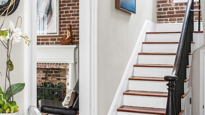 A entryway with a staircase featuring no carpet, dark wood steps and white risers, and a black handrail.