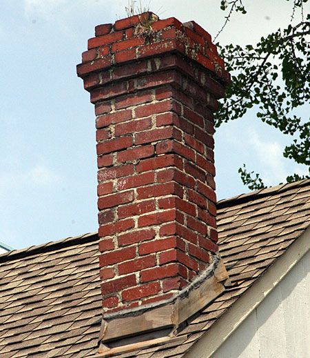 A red brick chimney on top of a home.