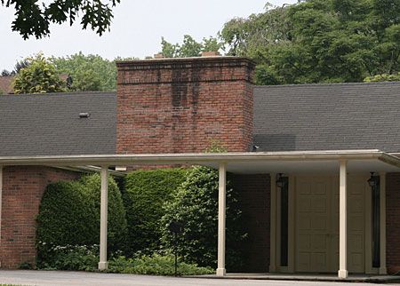 A wide chimney on top of a geometric home.