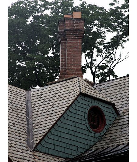 A brick chimney on top of an angled roof.