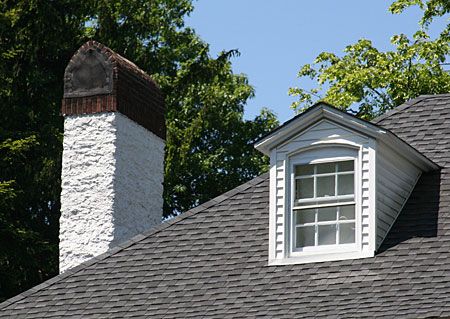 A stucco faced chimney on top of a curved roof.