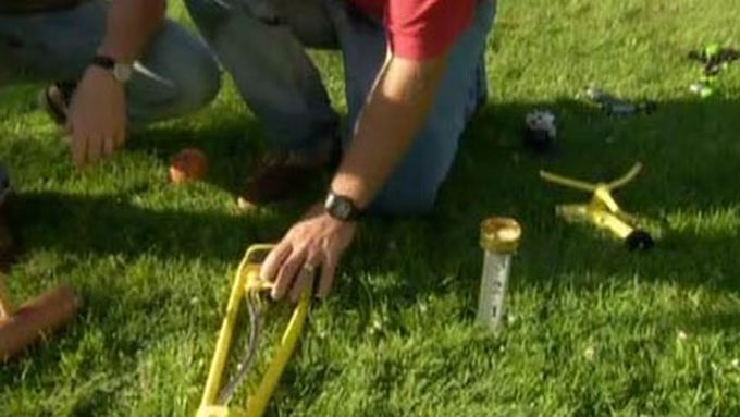 A man placing a sprinkler on a lawn.