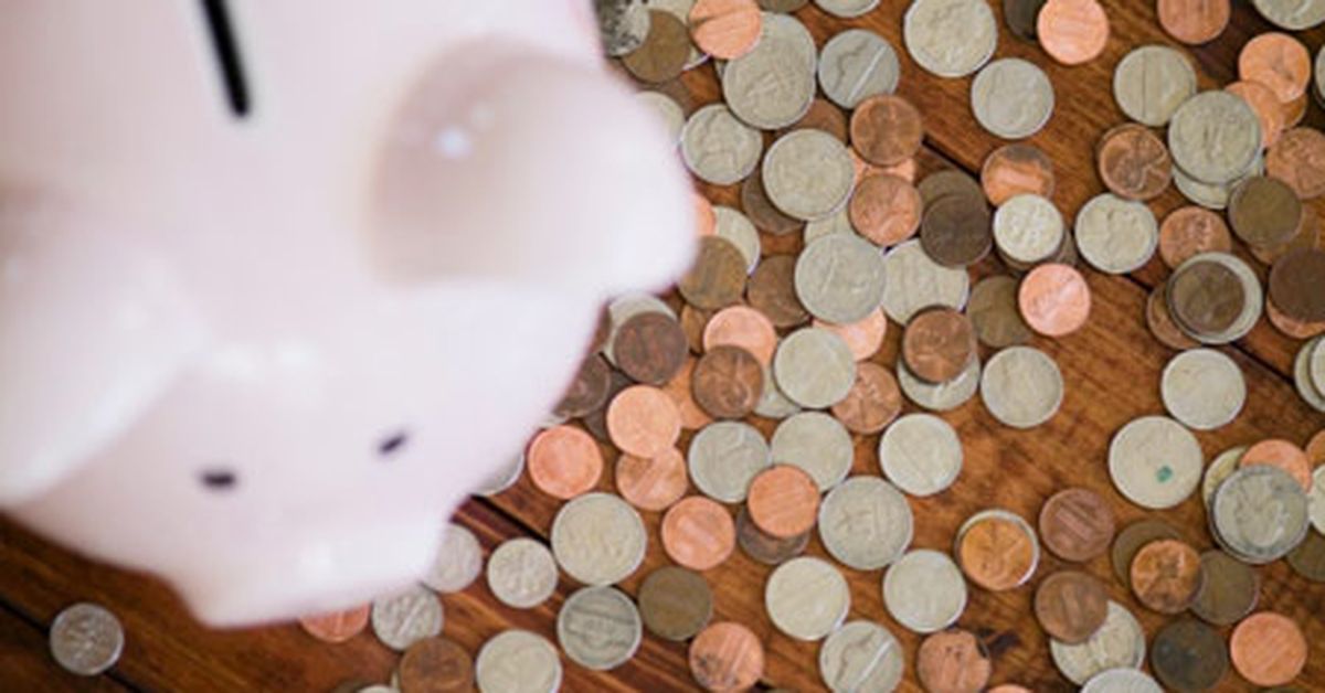 A piggy bank on top of a pile of coins.