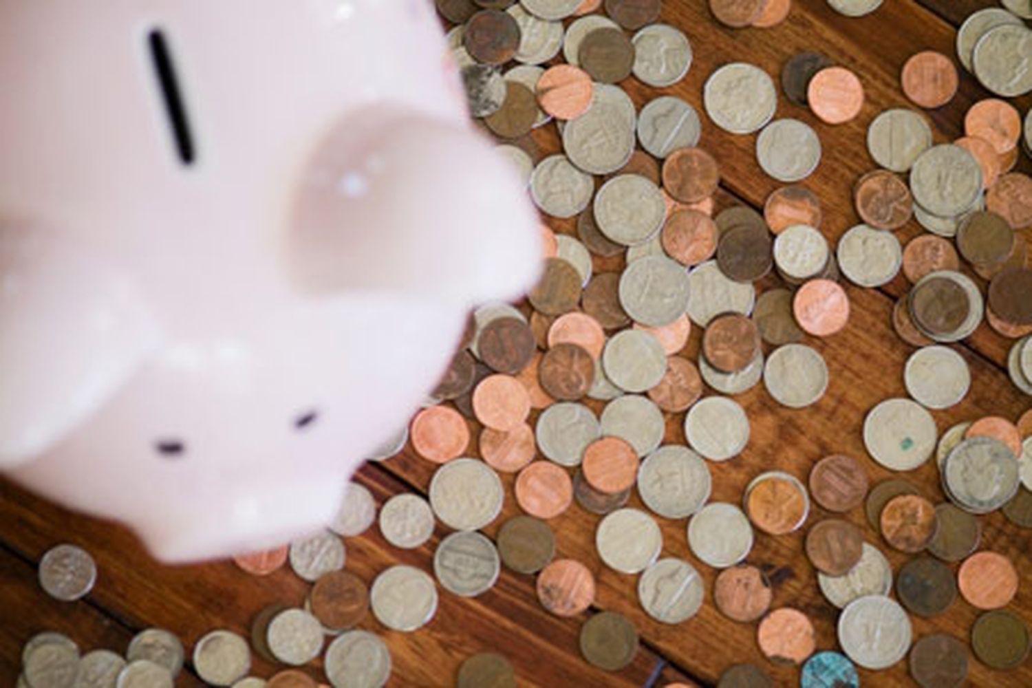A piggy bank on top of a pile of coins.