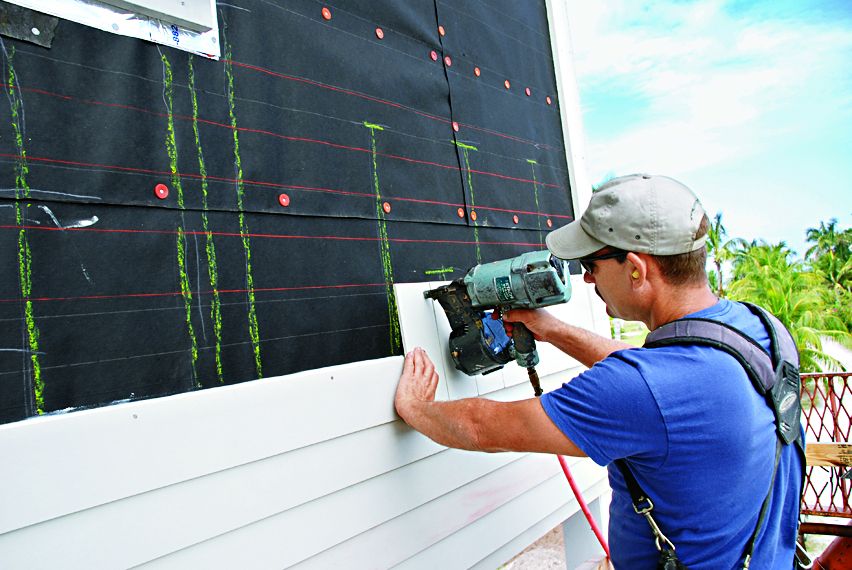 Construction worker installing fiber cement siding.