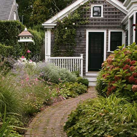 a brick path leading to a house in a cottage garden