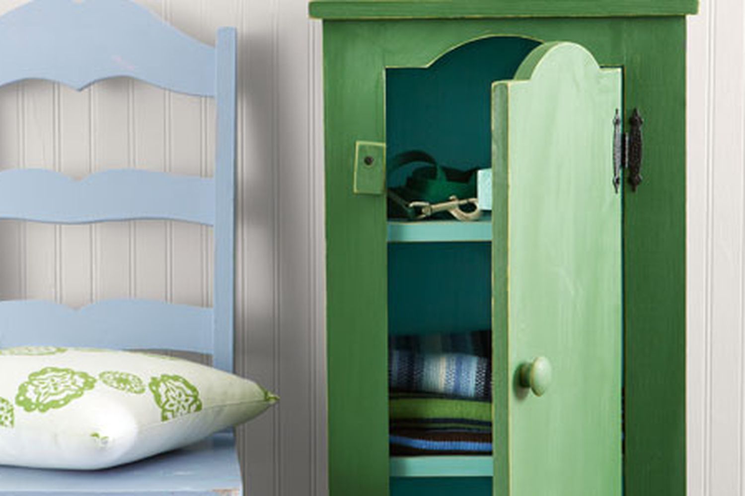 A green jelly cupboard beside a blue chair with a pillow on its seat.