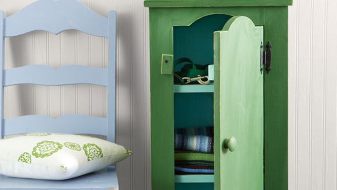 A green jelly cupboard beside a blue chair with a pillow on its seat.