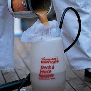 A new deck stain is poured through a filter before refurbishing a deck.