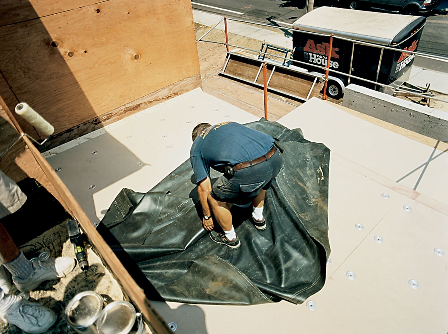 A man rolling out a at of EPDM for dry fitting a roof.