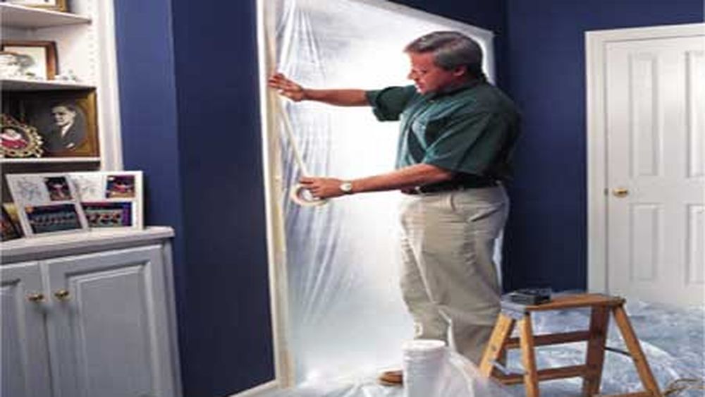 a man places plastic sheeting over an entryway to reduce dust transfer