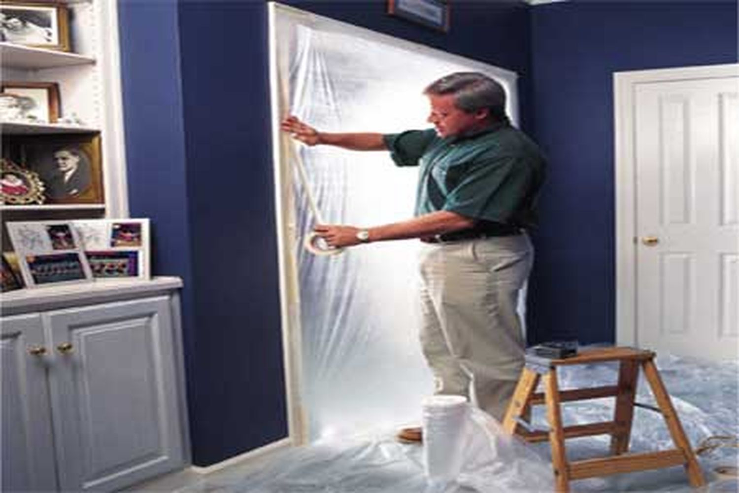 a man places plastic sheeting over an entryway to reduce dust transfer