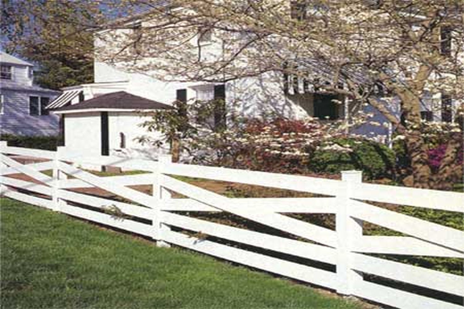 A white painted crisscross fence by a white house.
