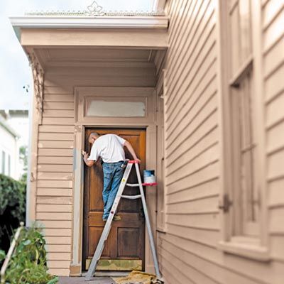 a man on a ladder painting a home