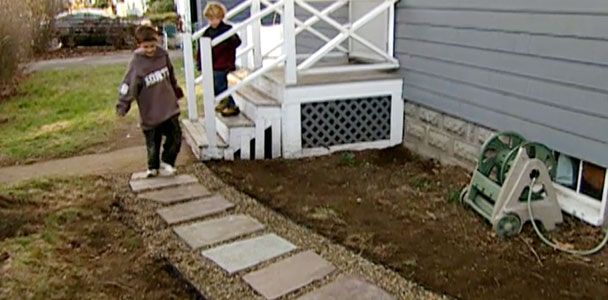 A child walking across a stone and gravel pathway next to a house.