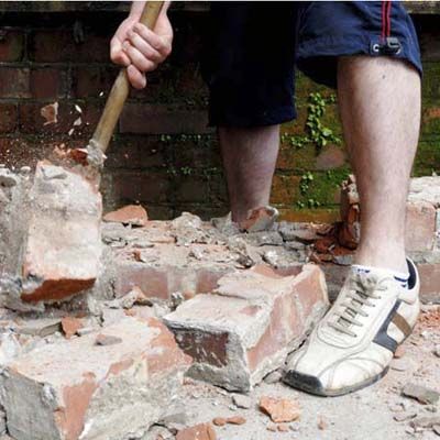 a man smashes bricks to help repair structural damage to his home