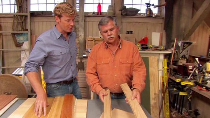 Two men in front of a table with several flooring options on top of it.