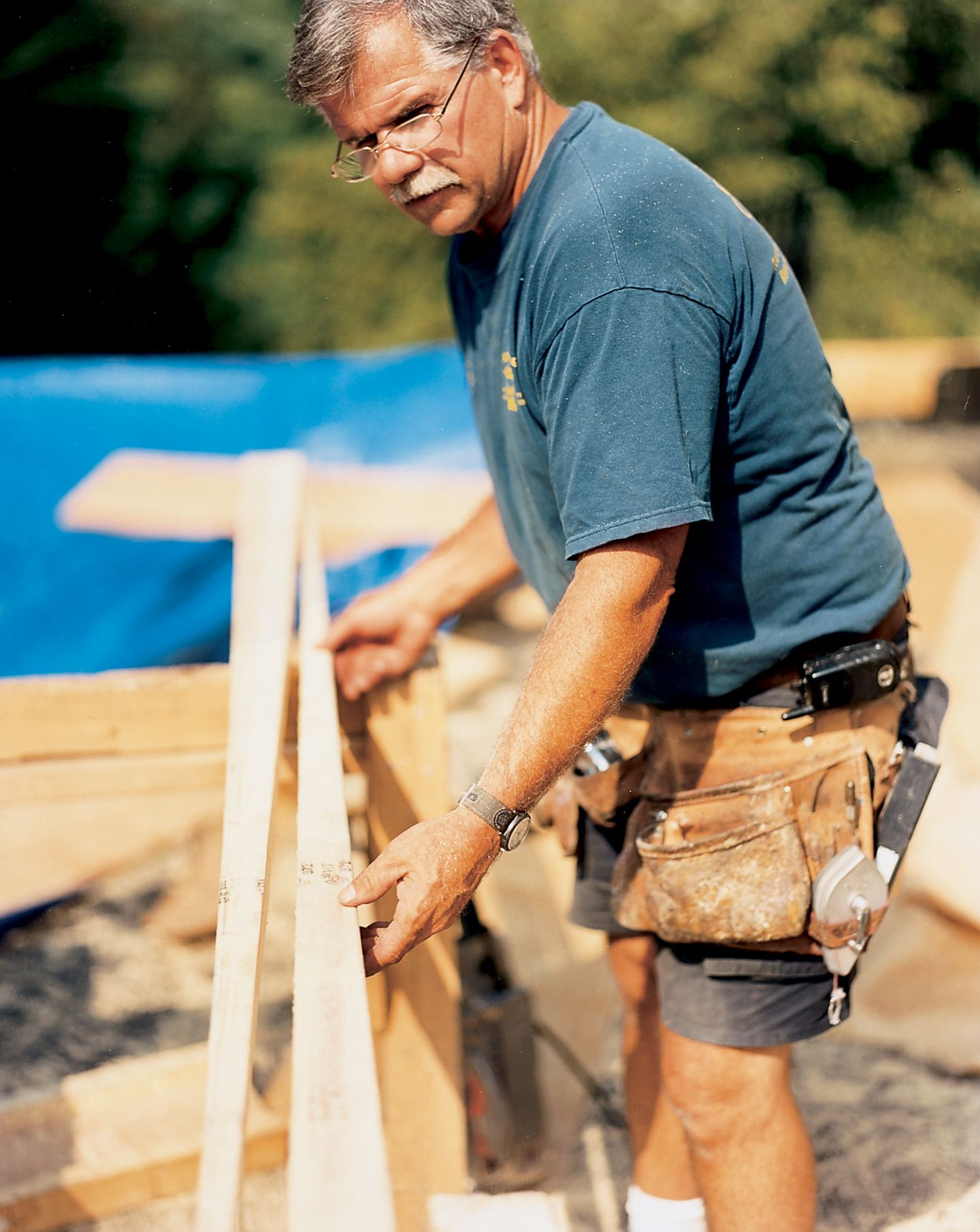 A man holding a wooden beam for framing a roof.