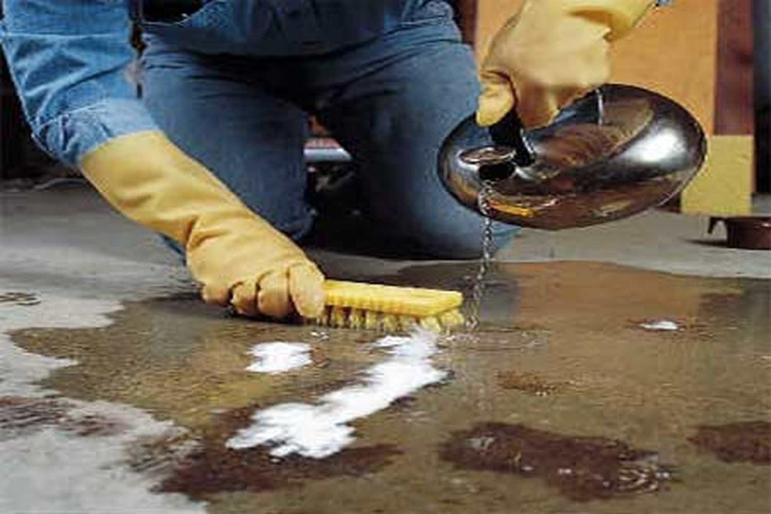 A man pouring a cleaning fluid and scrubbing a grease stain