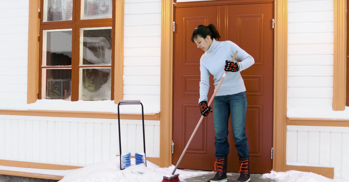 A woman deicing her front porch in winter.