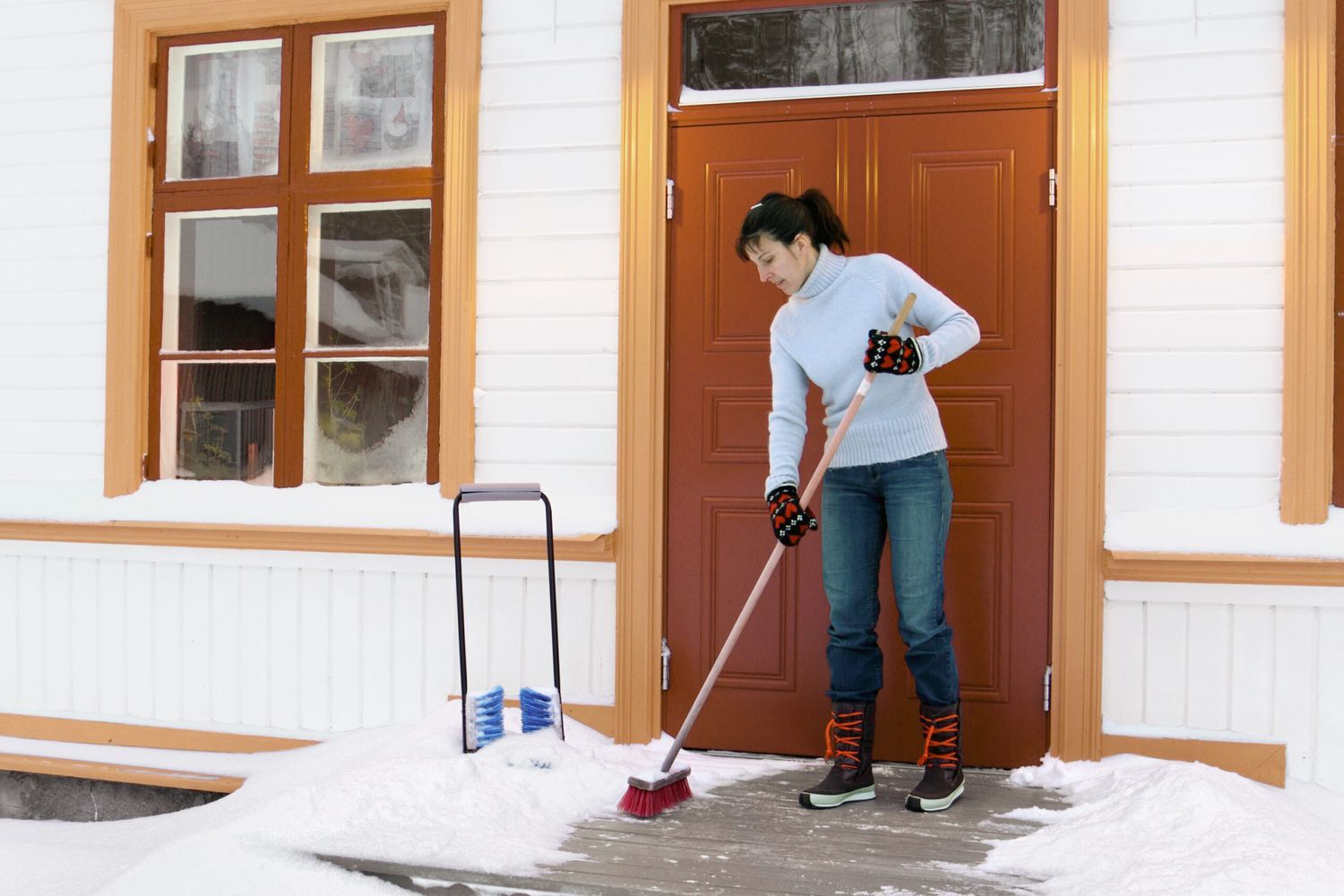 A woman deicing her front porch in winter.