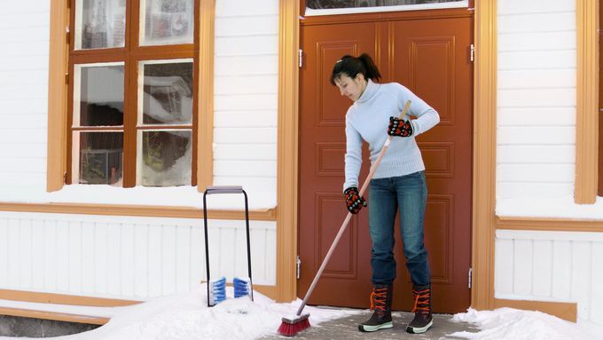 A woman deicing her front porch in winter.