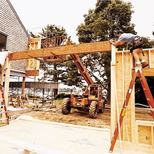 A house framing beam is installed using a forklift.