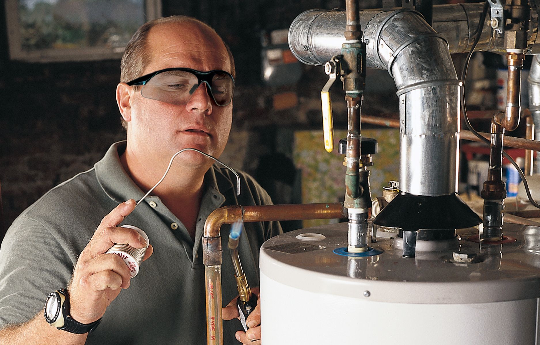 Photo of This Old House plumbing expert Richard Trethewey fixing a pipe.